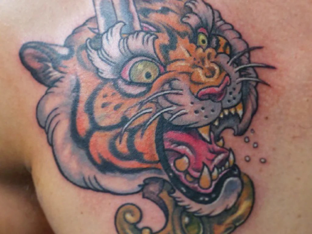 50 Animal Tattoo Ideas: The Complete Guide by Animal, Style and Placement 10 Traditional colour tiger head tattoo with bared teeth on a shoulder