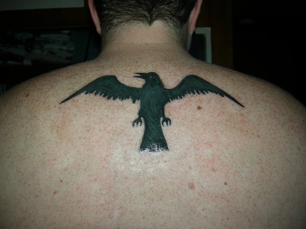 50 Animal Tattoo Ideas: The Complete Guide by Animal, Style and Placement 34 Solid black raven tattoo with wings spread across an upper back
