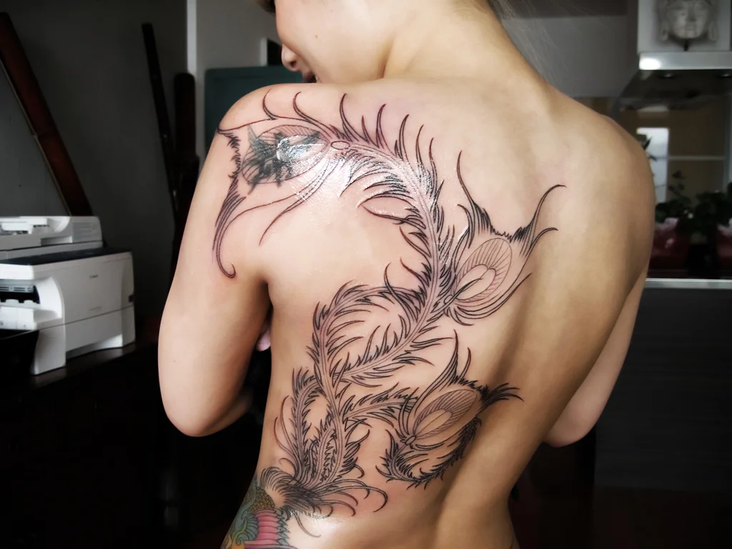 50 Animal Tattoo Ideas: The Complete Guide by Animal, Style and Placement 39 Black outline phoenix tattoo across a woman's back