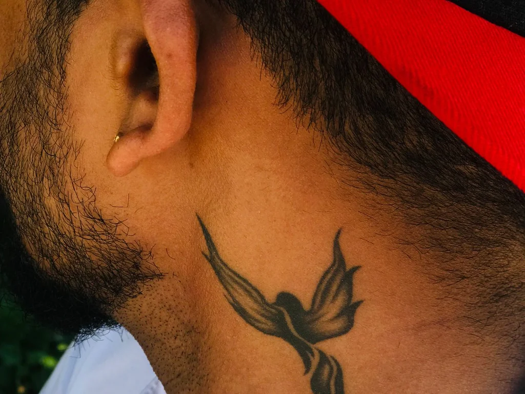 35 Bird Tattoo Ideas: Meanings, Species and Best Placements 4 Black swallow tattoo on the side of a man's neck