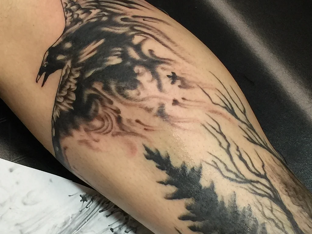 35 Bird Tattoo Ideas: Meanings, Species and Best Placements 27 Raven tattoo with pine trees on a forearm