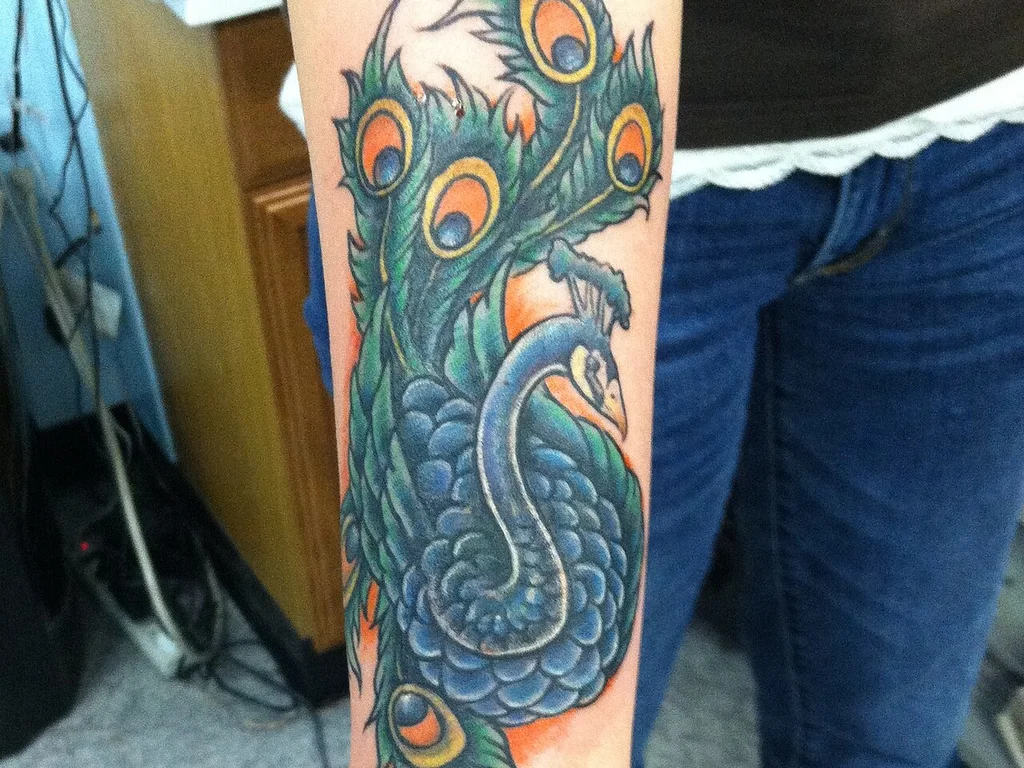 35 Bird Tattoo Ideas: Meanings, Species and Best Placements 34 Colourful peacock tattoo on a forearm