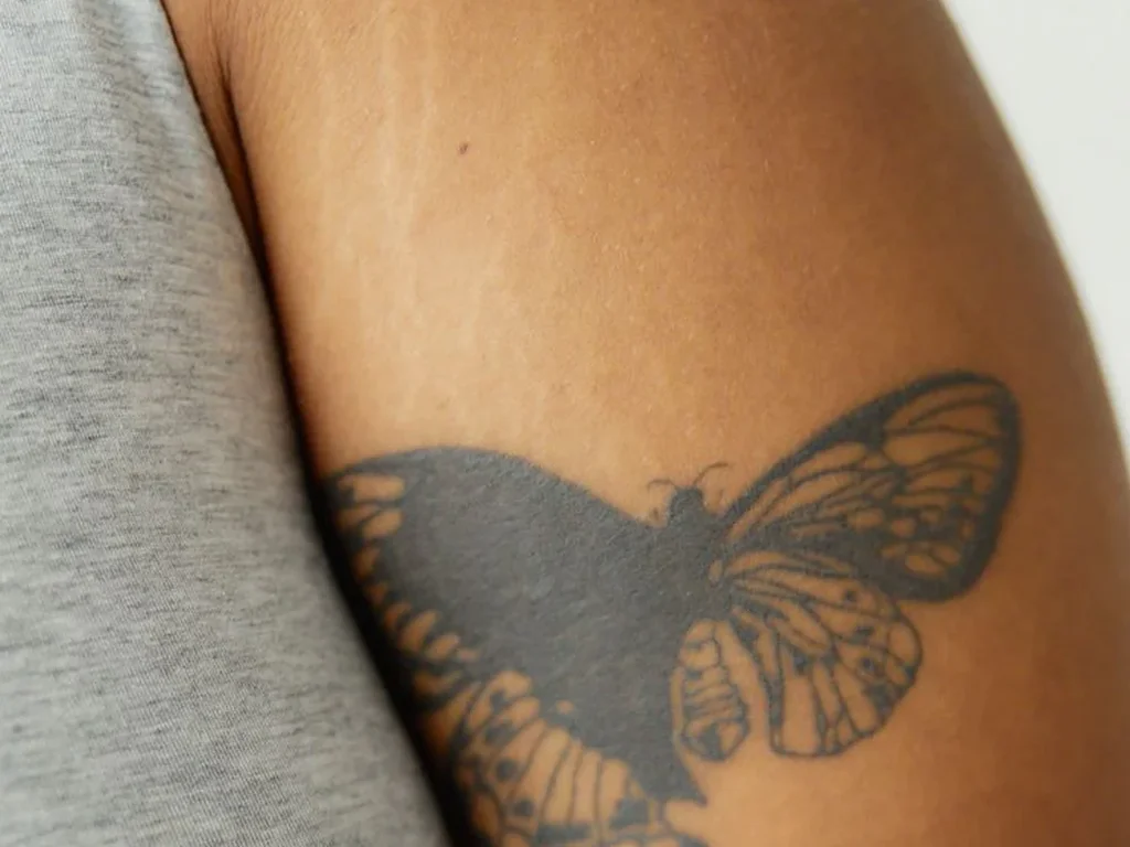 22 Butterfly Tattoo Ideas: Meanings, Styles and Best Placements 6 Black and grey shaded butterfly tattoo on an upper arm