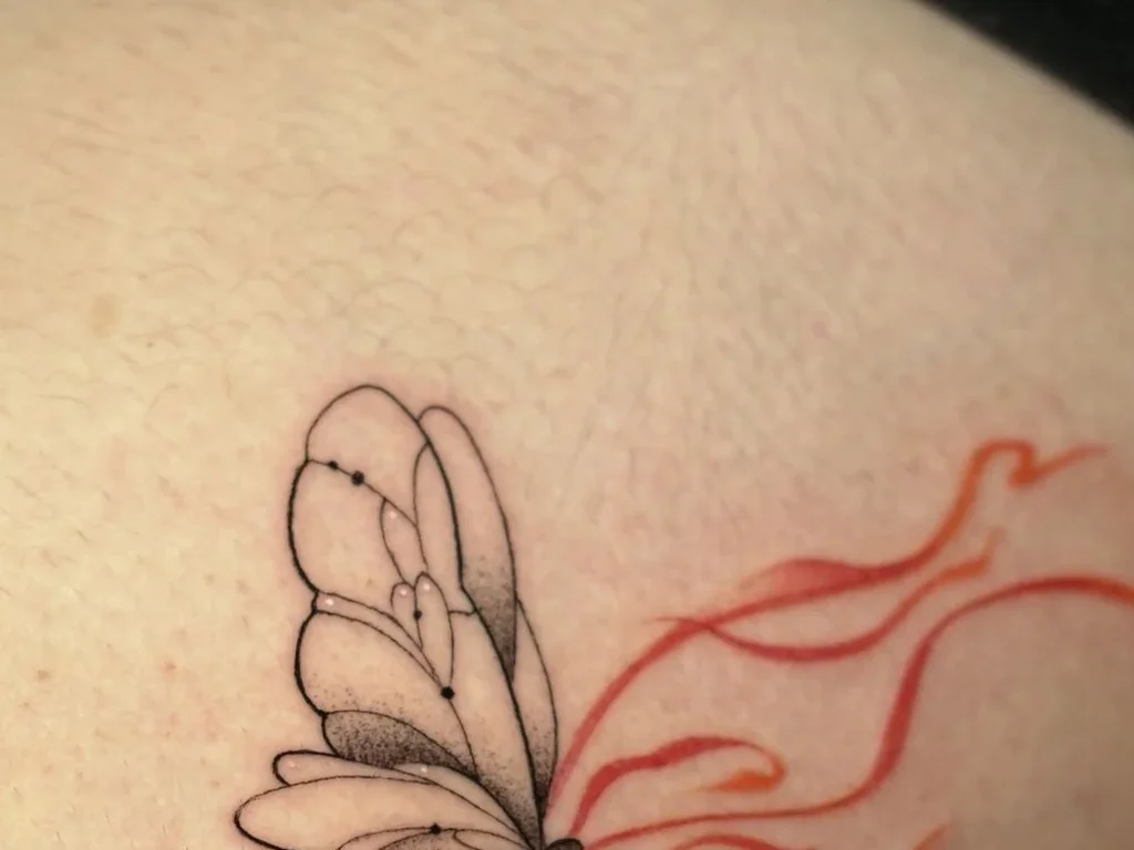 22 Butterfly Tattoo Ideas: Meanings, Styles and Best Placements 10 Fine-line butterfly tattoo with red swirl trails on ribs