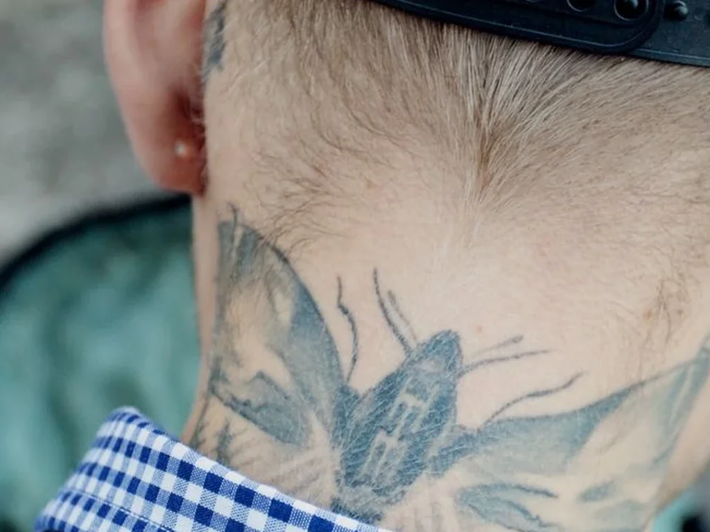 22 Butterfly Tattoo Ideas: Meanings, Styles and Best Placements 21 Grey moth tattoo across the back of a man's neck