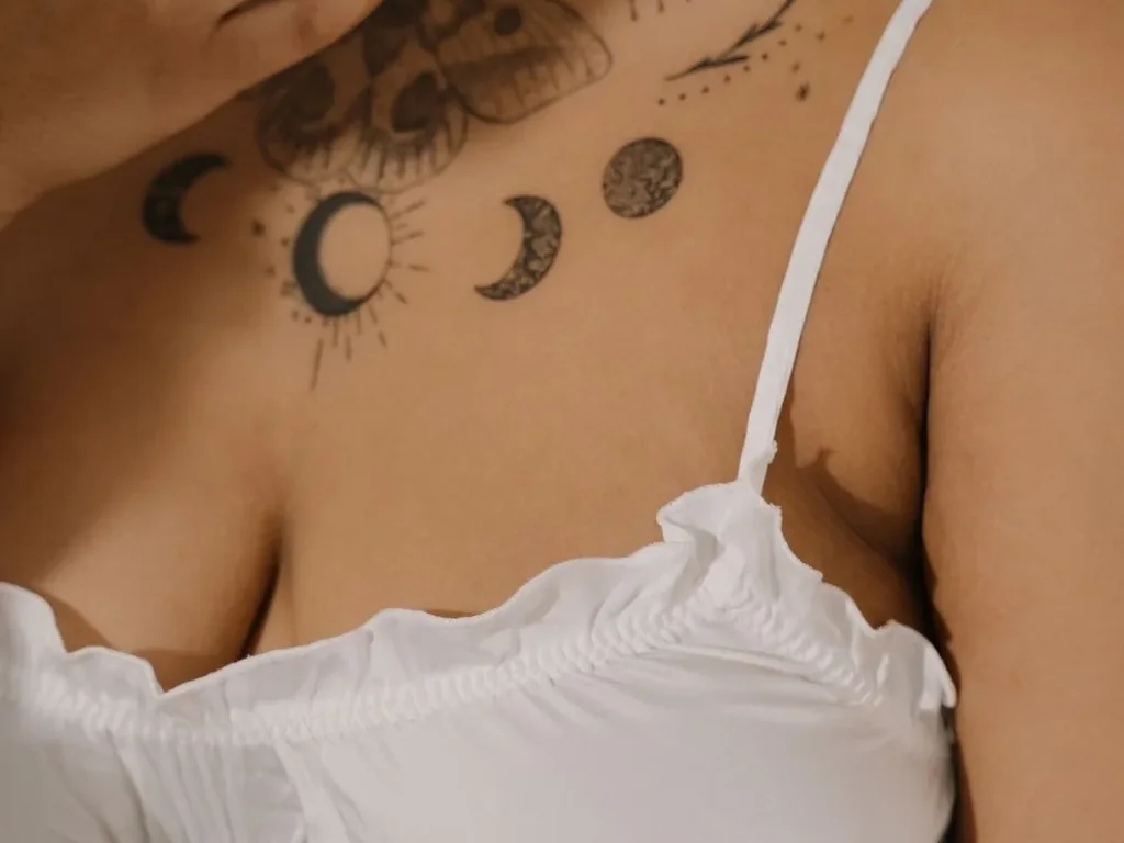 25 Fine Line Tattoo Ideas: Delicate Designs, Honestly Rated 7 Row of moon phase tattoos in fine line across a woman's upper chest