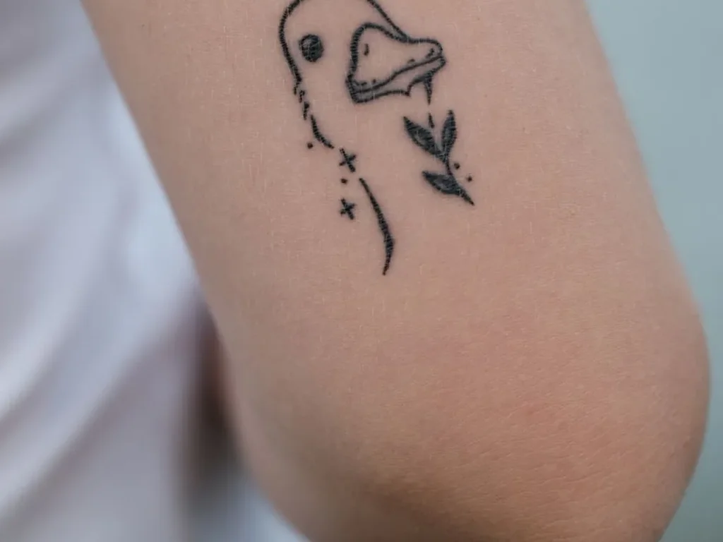 25 Fine Line Tattoo Ideas: Delicate Designs, Honestly Rated 14 Tiny fine line duck tattoo with a small leafy sprig on an inner arm