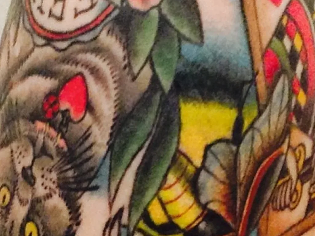 22 Pet Tattoo Ideas: Portraits, Paw Prints and Memorials Done Right 10 Traditional colour tattoo of a cats face with flowers and a large moth on an arm