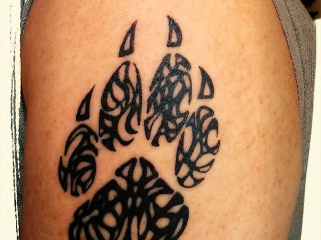 22 Pet Tattoo Ideas: Portraits, Paw Prints and Memorials Done Right 15 Bold black tribal patterned paw print tattoo on an upper arm