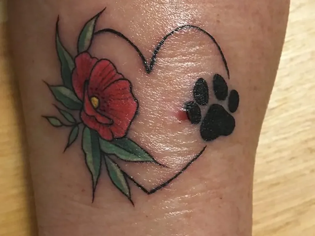 22 Pet Tattoo Ideas: Portraits, Paw Prints and Memorials Done Right 19 Heart outline tattoo with a red poppy and a black paw print on a forearm