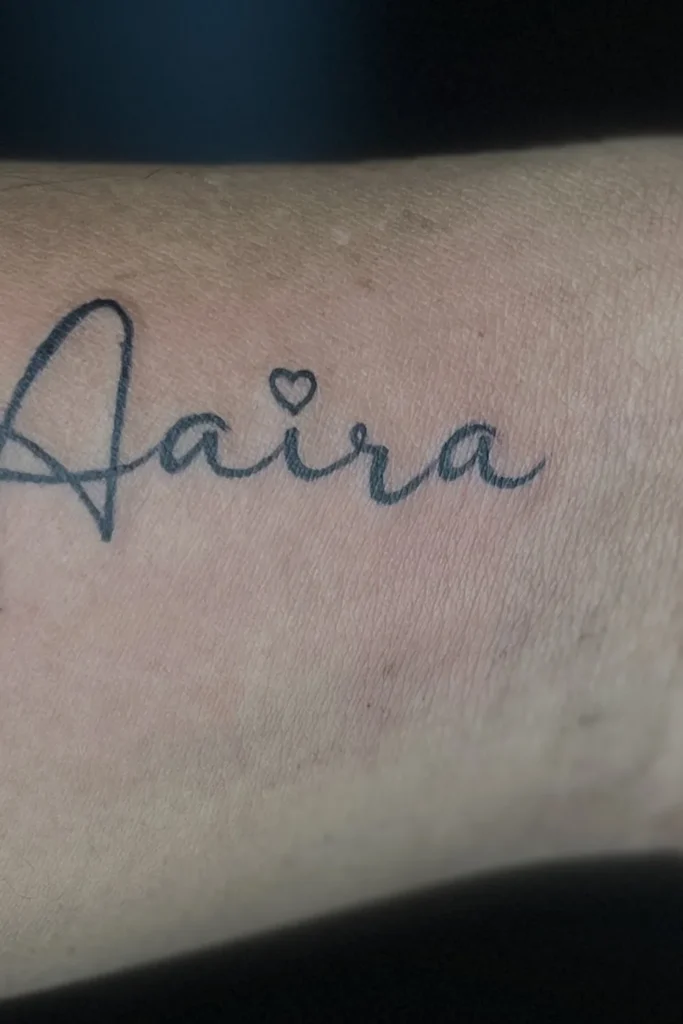Name tattooed in fine cursive script across the inner wrist