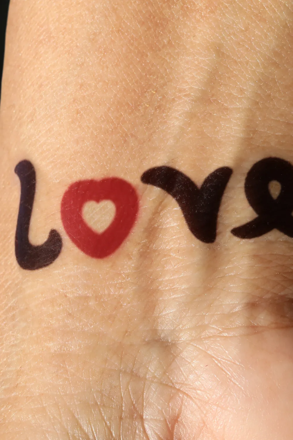 23 Small Tattoos for Women: Tiny Designs That Say a Lot, Quietly 4 Matching ambigram word tattoos on both wrists, one reading love with a red heart