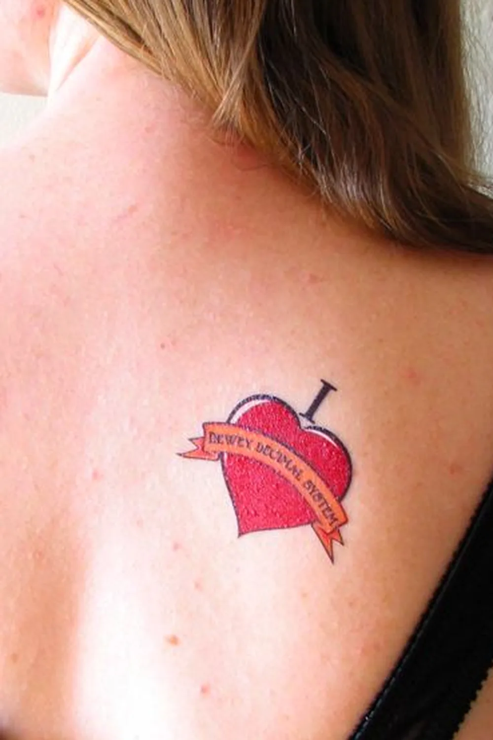 23 Small Tattoos for Women: Tiny Designs That Say a Lot, Quietly 13 Red heart tattoo with a banner across it on the shoulder blade