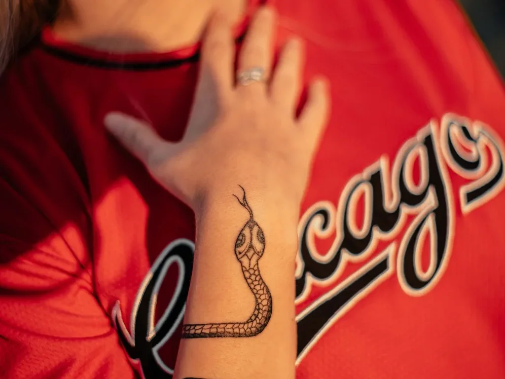 20 Snake Tattoo Ideas: Meanings, Styles and Placements That Work 7 Black snake tattoo with fine scales wrapping a wrist and forearm, head raised