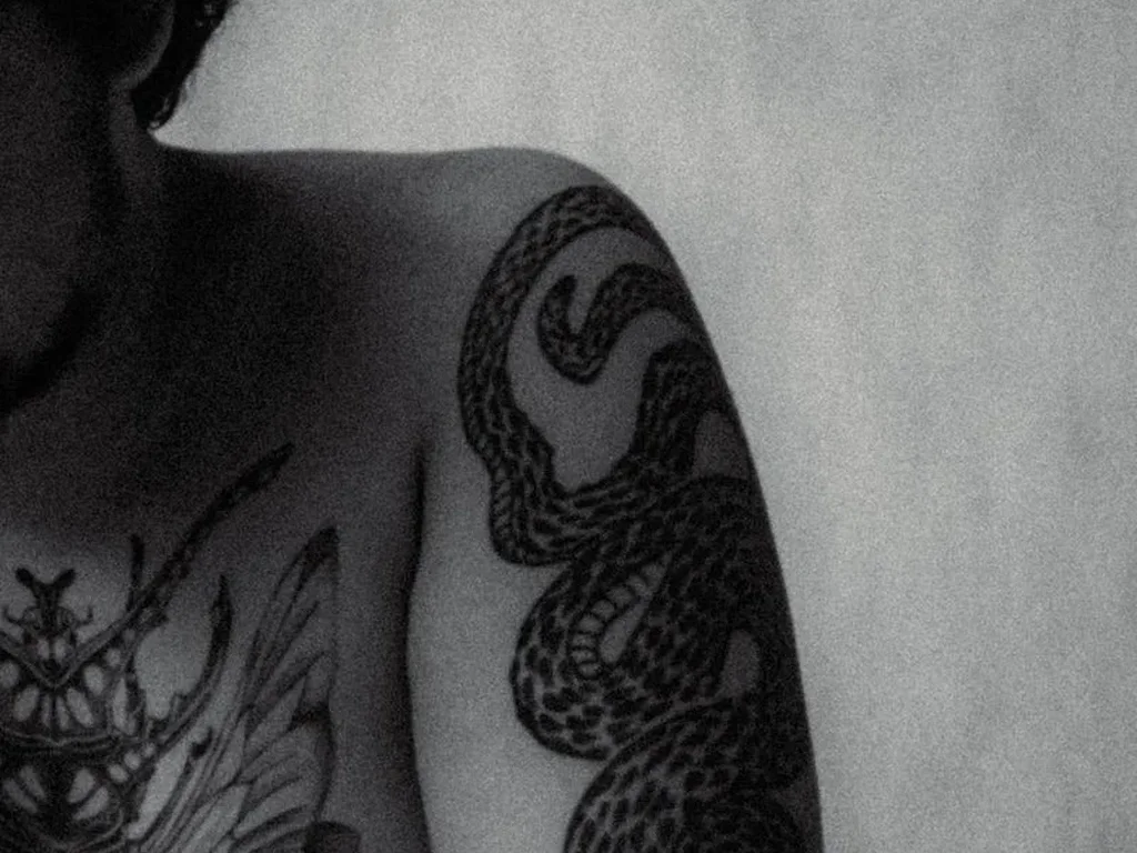 20 Snake Tattoo Ideas: Meanings, Styles and Placements That Work 9 Heavy blackwork snake tattoo with stippled scales on an upper arm